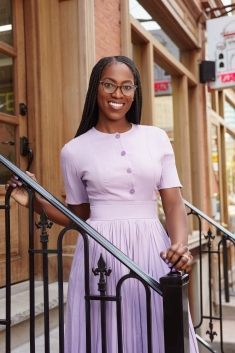 woman in lavender dress on outside staircase smiling