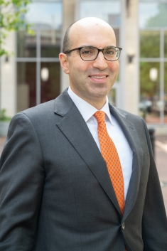 man wearing glasses smiling outside of law school building