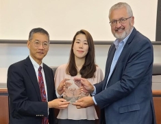 Three people holding an award and posing for a photograph