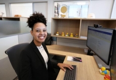 woman in a suit sitting at a desk and posing for a photograph