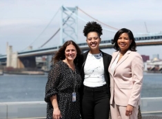 three women posing for a photograph in front of a bridge