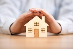 a miniature house covered by hands