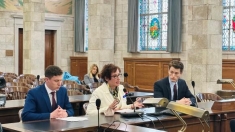 Formally dressed people sitting behind a large desk