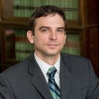 Man in suit grinning in front of bookcase