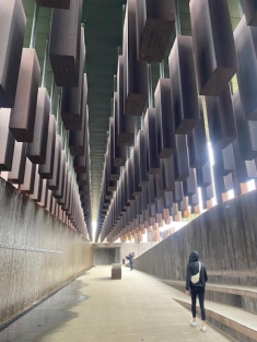 man in a hoodie walking through an artsy hallway