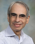Man smiling with glasses wearing a blue button down shirt 