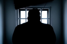 man looking out a window with bars