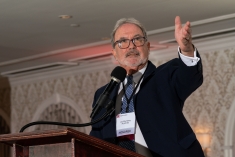 Man speaking at podium with raised arm