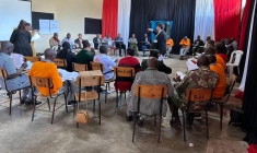 Man standing in the middle of circles of people seated in classroom chairs