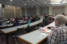 large audience of people seated in semi circle rows in classroom