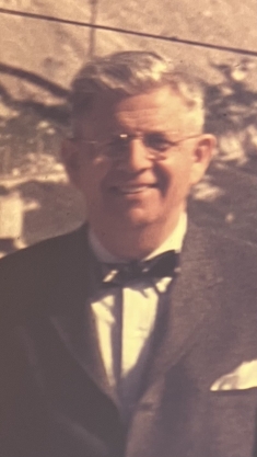 man in wire rimmed glasses and bow tie/suit smiling outside