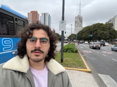 man wearing glasses posing in busy traffic intersection