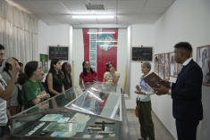 group listening to man speaking on the other side of a glass showcase