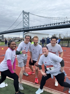group of people in matching shirts smiling on race track with bridge in background