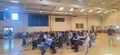 people seated in rows in large gym
