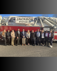 group of men and women standing side by side on side of red firetruck