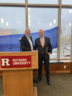 two men in suits standing side by side and smiling behind podium