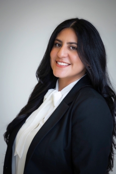 woman with long hair in dark blazer and white blouse smiling