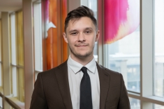 man in suit and tie grinning in front of large colorful window