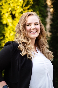 woman in black blazer and white blouse smiling outside
