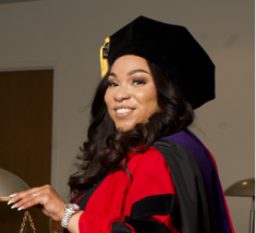 woman with long hair smiling in black graduation cap and hood with red robe