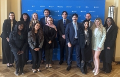 men and women standing in a group in business attire in front of blue background