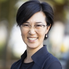 woman with short hair wearing glasses and smiling outdoors