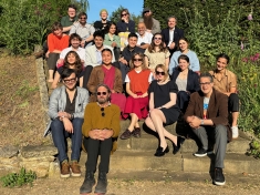 group of men and women sitting on steps outside in grassy area