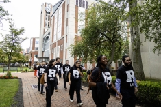 procession of people in black and white shirts walking in lines in outdoor plaza