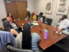 group of people in conference room seated around table listening to woman