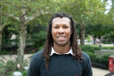 Man in dark shirt smiling outdoors