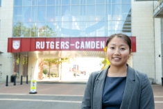 woman in business suit smiling in front of Rutgers-Camden overpass