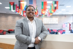 woman smiling on ramp in front of different national flags hanging from ceiling