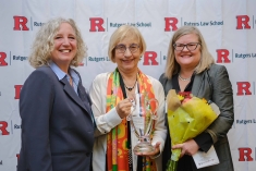three women standing next to each other and smiling in front of Rutgers Law background