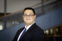 man in dark suit wearing glasses and grinning
