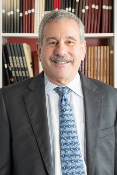 man in suit smiling in front of the bookcase