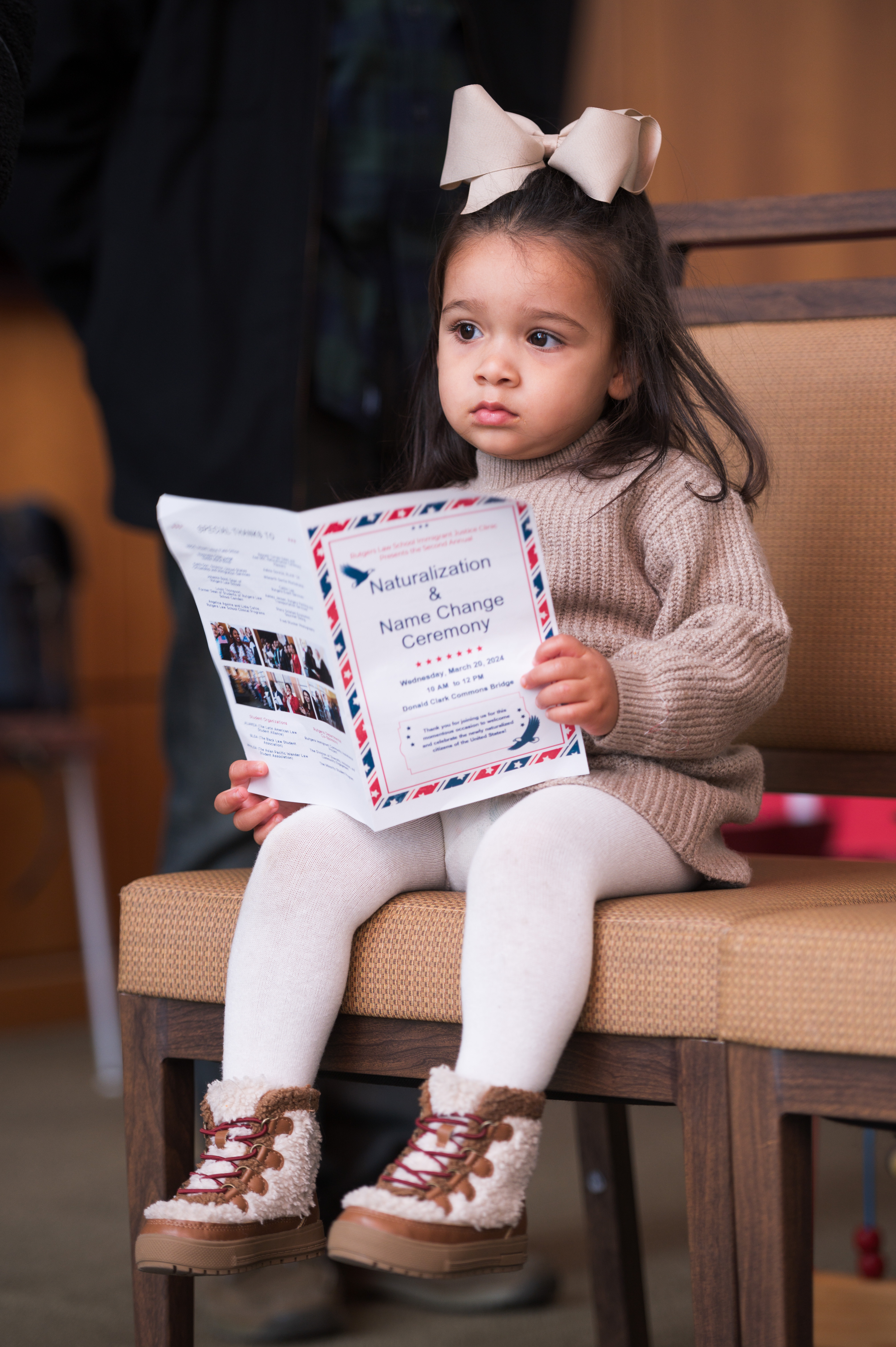 Toddler sitting with program in hand