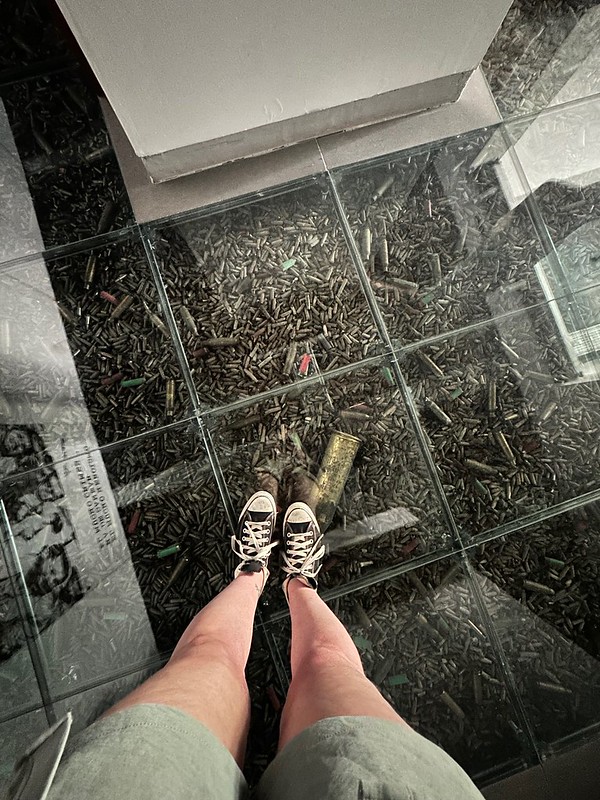 feet standing on top of glass enclosure with bullet casings underneath in cuba