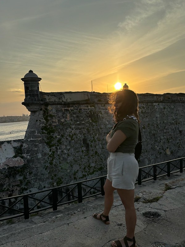 woman looking over fort to water during sunset in cuba