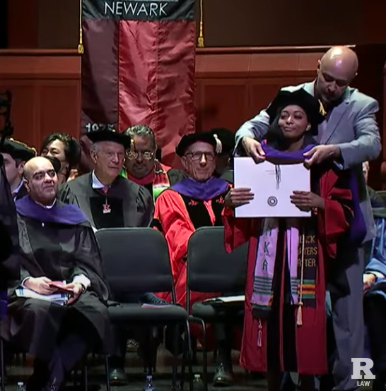 man hooding woman on commencement stage