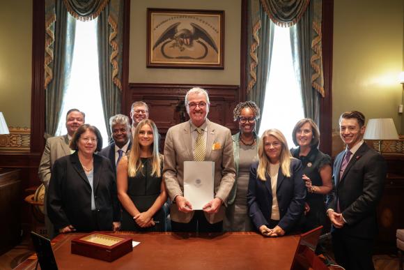 NJ Gov. Phil Murphy (center) signs law offering protections to stalking/cyber harassment survivors against people they never dated or lived with, thanks in part to the work of Nick Gangemi '23 (far right).