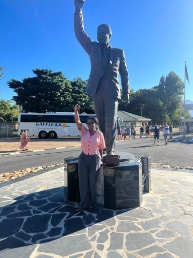 woman with raised fist in front of nelson mandela statue