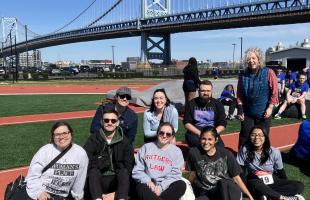 group of law students sitting on athletic field near ben franklin bridge