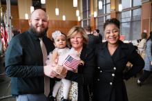 Man, baby and two women smiling with American flag