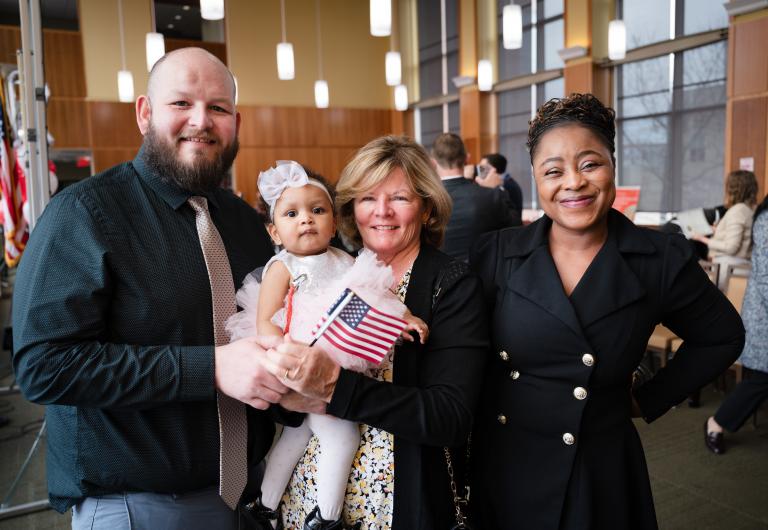 Man, baby and two women smiling with American flag
